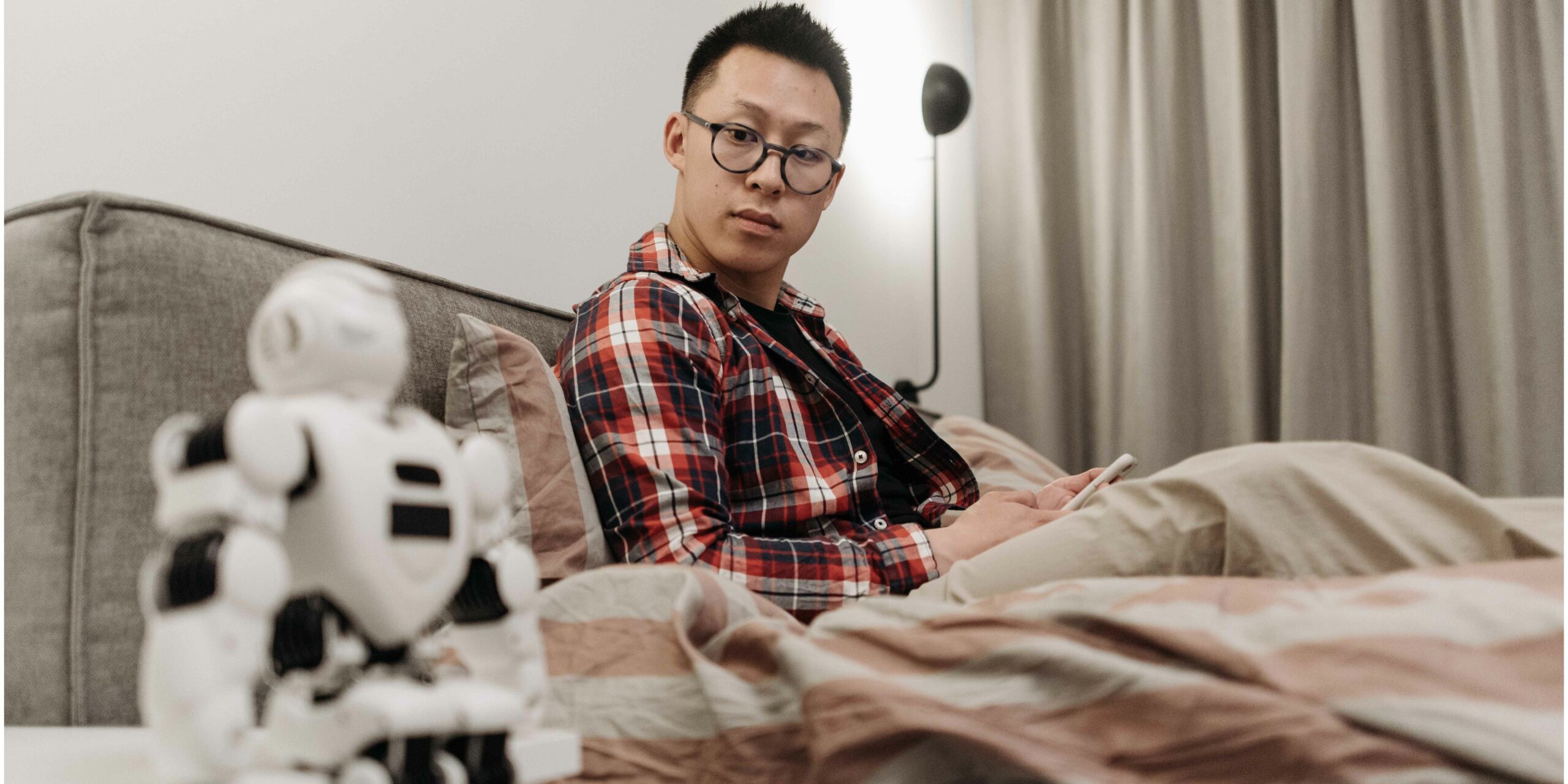 man-sitting-on-bed-observing-an-ai-robot-late-at-night